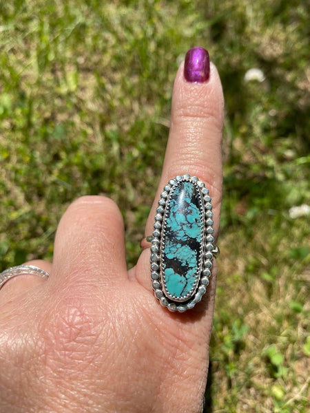 One of a kind handcrafted ring.  Eye-catching natural turquoise oblong stone set in a decorative sterling silver ring. What a stunner!  Available in US size 10 for a perfect pointer finger fit.  Turquoise, the captivating sea-green stone of the ancients, represents wisdom, tranquility, protection, good fortune, and hope.  Ships out within 1 to 2 business days. (Not including weekends or holidays)