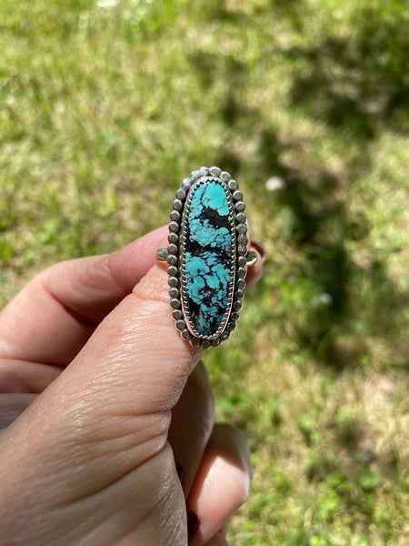 One of a kind handcrafted ring.  Eye-catching natural turquoise oblong stone set in a decorative sterling silver ring. What a stunner!  Available in US size 10 for a perfect pointer finger fit.  Turquoise, the captivating sea-green stone of the ancients, represents wisdom, tranquility, protection, good fortune, and hope.  Ships out within 1 to 2 business days. (Not including weekends or holidays)